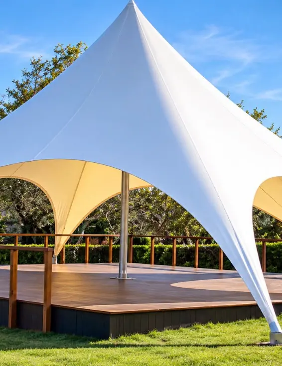 White tensile canopy over an open space among trees